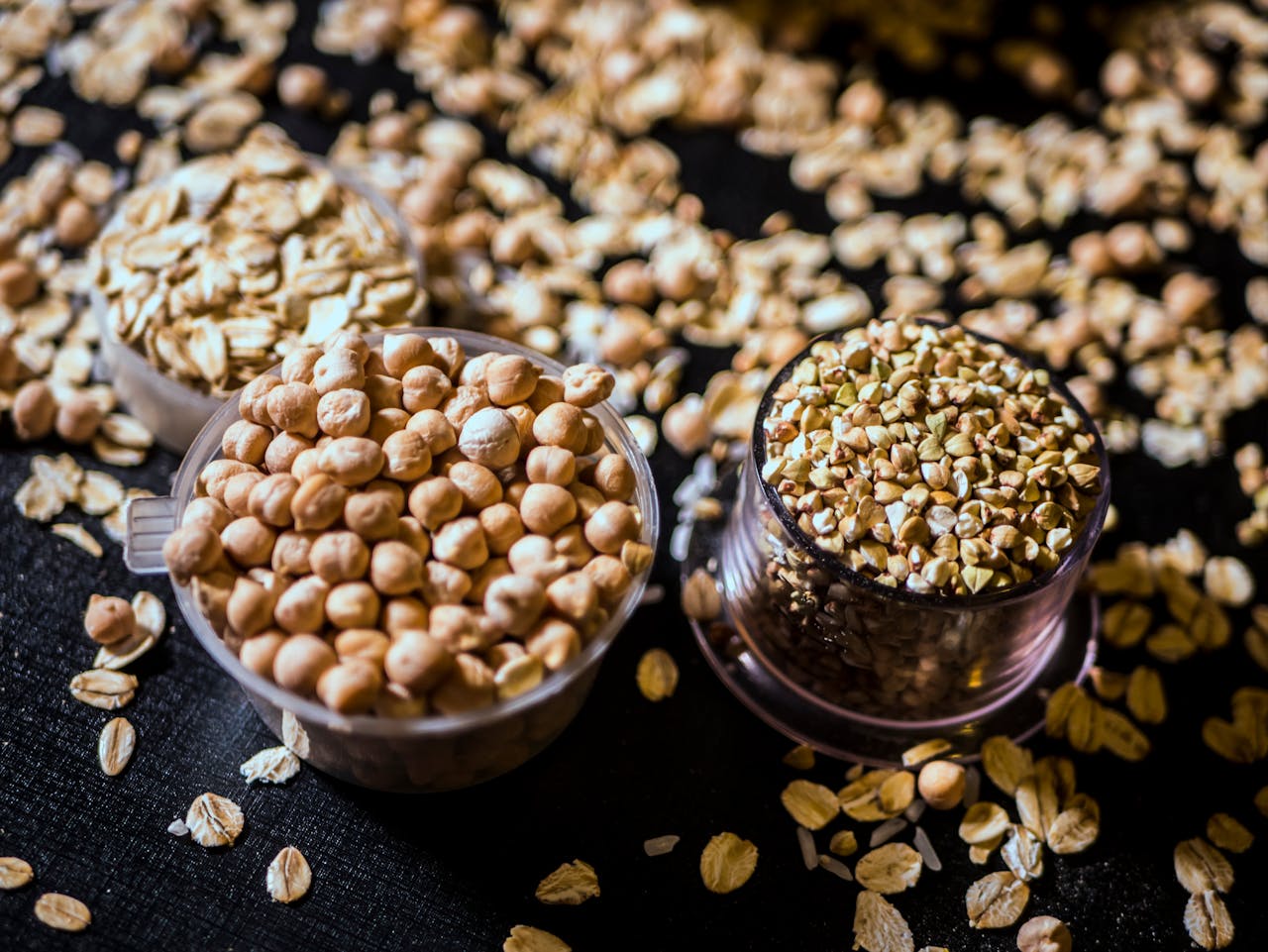 hero Close-up of assorted raw grains and seeds in cups on a dark background, showcasing variety and texture.