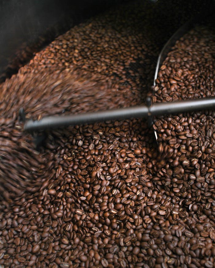 services-01 A dynamic close-up of coffee beans being roasted, highlighting the process.